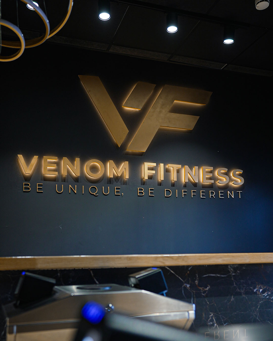 Logo Venom Fitness dorado en pared del gimnasio